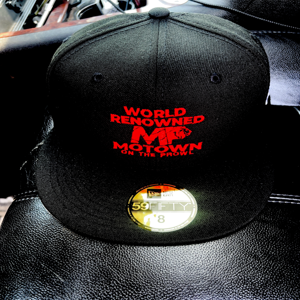 Black cap with red text and a gold sticker on the brim.