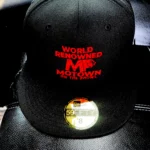 Black cap with red text and a gold sticker on the brim.