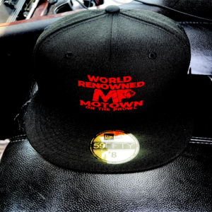 Black cap with red text and a gold sticker on the brim.