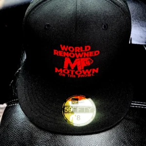 Black cap with red text and a gold sticker on the brim.
