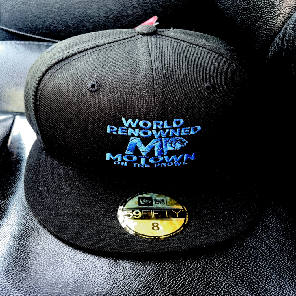 Black baseball cap with blue and white embroidered text.