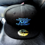Black baseball cap with blue and white embroidered text.