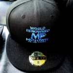 Black baseball cap with blue and white embroidered text.
